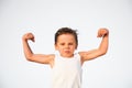 Funny little caucasian kid with grimace on his face showing biceps muscle