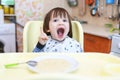 Funny little child eating wheat porridge with pumpkin