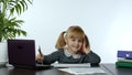 Funny little child girl boss manager emotionally talking on mobile phone, sitting at computer table Royalty Free Stock Photo