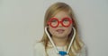 Funny little child girl wear red glasses holding stethoscope playing game as doctor, happy cute adorable small preschool Royalty Free Stock Photo