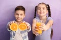 Funny little children with citrus fruit and juice on color background