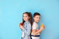 Funny little children drinking citrus juice on color background