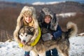 Funny little children hugging dog in winter outdoor. Smiling kids friends in frost snowy day outdoor. Two kids boys an