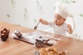 Funny little cook in kitchen playing with cookie cutters and flour Royalty Free Stock Photo
