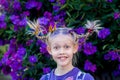 Funny little cute caucasian girl with braids for crazy hair day at school on purple flowers tibouchina nature outside background