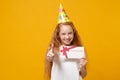 Funny little ginger kid girl 12-13 years old in white t-shirt, birthday hat isolated on yellow background. Childhood Royalty Free Stock Photo