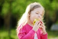 Funny little girl biting an apple outdoors on warm and sunny summer day. Royalty Free Stock Photo