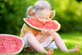 Funny little girl biting a slice of watermelon outdoors Royalty Free Stock Photo