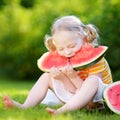 Funny little girl biting a slice of watermelon outdoors Royalty Free Stock Photo