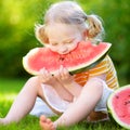 Funny little girl biting a slice of watermelon outdoors Royalty Free Stock Photo