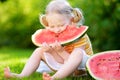 Funny little girl biting a slice of watermelon outdoors Royalty Free Stock Photo