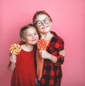 Funny little girl and boy holding sugar lollipop. Laughing kids eating candy isolated on colorful background. Delighted Royalty Free Stock Photo