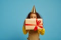 Funny little girl in cap holds birthday gift box Royalty Free Stock Photo