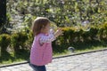 Funny little girl catching soap bubbles. Carefree child Running and jumping in park, springtime. Royalty Free Stock Photo