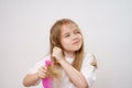 funny little girl combs long and tangled hair. white background.