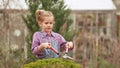 a funny little girl cuts bushes in the garden with large pruner.