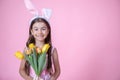 Funny little girl with easter bunny ears holding a bouquet of spring flowers copy space Royalty Free Stock Photo