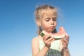 Funny little girl eat watermelon sunny summer day at ocean beach. Cute caucasian female child enjoy summer fruit bite slice of Royalty Free Stock Photo