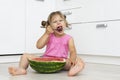 Funny little girl eating watermelon with a big spoon Royalty Free Stock Photo