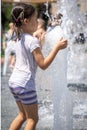 Funny little girl in the fountain plays with splashes of water Royalty Free Stock Photo