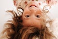 Funny little girl hanging from the table over the camera, head upside down Royalty Free Stock Photo