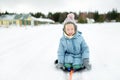 Funny little girl having fun with a sleigh in beautiful winter park. Cute child playing in a snow Royalty Free Stock Photo