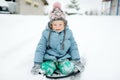 Funny little girl having fun with a sleigh in beautiful winter park. Cute child playing in a snow Royalty Free Stock Photo