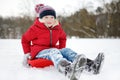 Funny little girl having fun with a sleigh in beautiful winter park. Cute child playing in a snow. Royalty Free Stock Photo