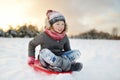 Funny little girl having fun with a sleigh in beautiful winter park. Cute child playing in a snow Royalty Free Stock Photo