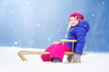 Funny little girl having fun with a sleight in beautiful winter park Royalty Free Stock Photo