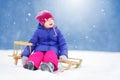 Funny little girl having fun with a sleight in beautiful winter park Royalty Free Stock Photo