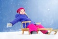 Funny little girl having fun with a sleight in beautiful winter park Royalty Free Stock Photo