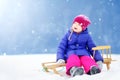 Funny little girl having fun with a sleight in beautiful winter park Royalty Free Stock Photo