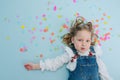 Funny little girl lies on a floor with a confetti pieces over her head Royalty Free Stock Photo