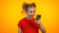 Funny little girl looking at smartphone screen and smiling, shopping application