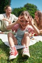 Funny little girl making faces at camera while relaxing with family outdoors, having picnic in nature on a summer day Royalty Free Stock Photo