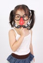 Funny little girl making faces with mustache props Royalty Free Stock Photo