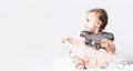 Funny little girl in a pink dress. Portrait of a cute baby 6 months old lying on a white blanket. Handsome baby. Looks into the Royalty Free Stock Photo