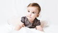 Funny little girl in a pink dress. Portrait of a cute baby 6 months old lying on a white blanket. Handsome baby. Looks into the Royalty Free Stock Photo