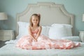 Funny little girl in pink dress sitting on bed Royalty Free Stock Photo