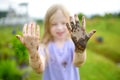 Funny little girl playing in a large wet mud puddle on sunny summer day. Child getting dirty while digging in muddy soil. Royalty Free Stock Photo