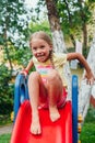 Funny little girl playing on a slide at a playground. Childhood. Summertime Royalty Free Stock Photo