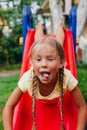 Funny little girl playing on a slide at a playground. Childhood. Royalty Free Stock Photo