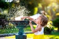 A funny little girl is playing with the spray of a drinking water fountain in the park. Childhood, child, summer time, heat. Solar Royalty Free Stock Photo