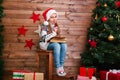 Funny little girl in Santa hat writes letter to Santa near christmas tree Royalty Free Stock Photo