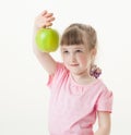 Funny little girl showing a green apple