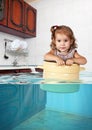 Funny little girl swim in pan in the flooded kitchen, making mes Royalty Free Stock Photo