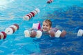 a funny little girl swims in inflatable armbands in a pool near the buoys.