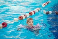 a funny little girl swims in inflatable armbands in a pool near the buoys. Royalty Free Stock Photo