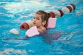 a funny little girl swims in inflatable armbands in a pool near the buoys. Royalty Free Stock Photo